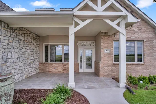 Brick and stone home features a covered porch with decorative beams and a double-door entry.