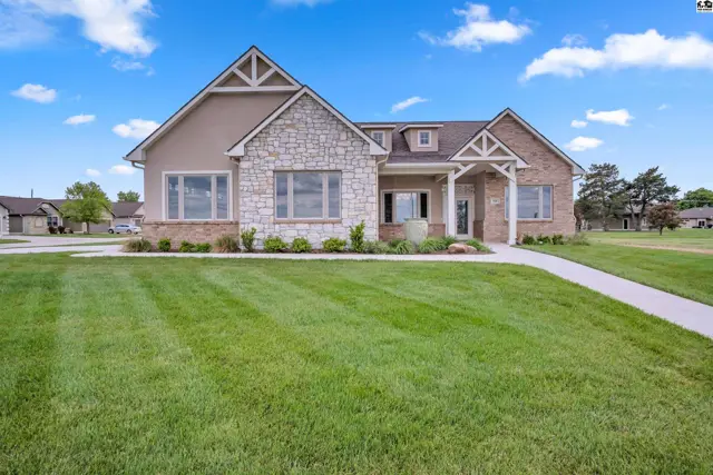 This home features stone and stucco exterior with a manicured lawn.