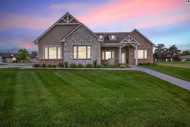 This home features stone and brick exterior with a manicured lawn.