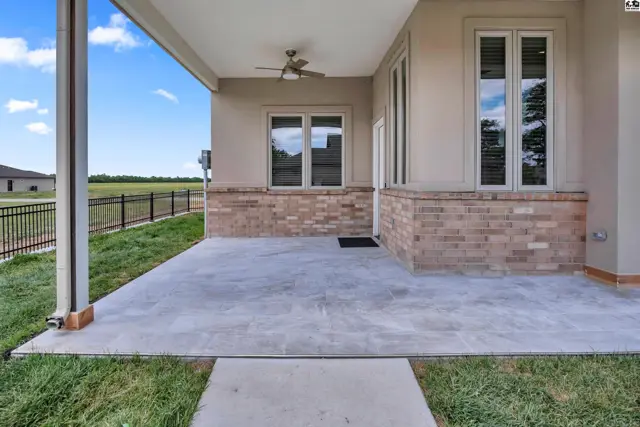 Covered patio with concrete floor, ceiling fan, and brick accents.