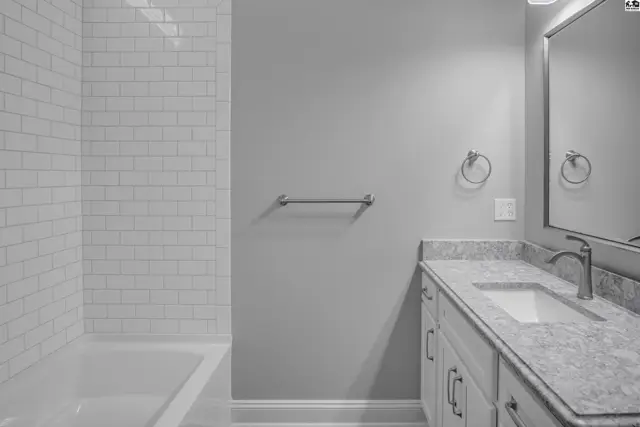 This bathroom features a white subway tile shower surround, a granite countertop vanity, and a large mirror.