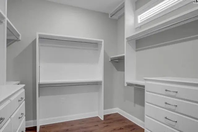 Spacious walk-in closet with built-in shelving, drawers, and hanging rods.