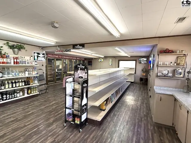 Interior view of a well-stocked convenience store with wood-look flooring and extensive shelving.
