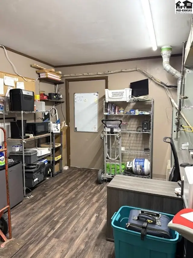 A utility room with laminate flooring, metal shelving, and various storage items.