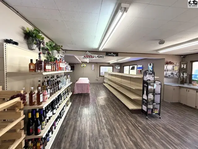 Interior of a retail store with shelves stocked with liquor and empty display shelves.