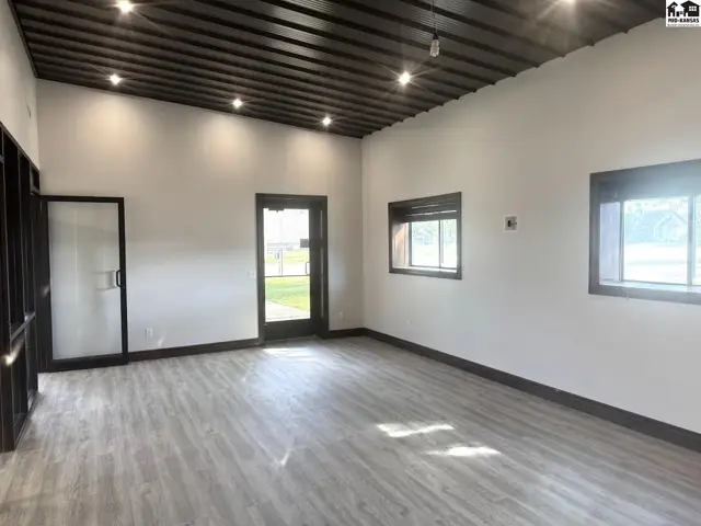 Spacious interior with white walls, dark wood ceiling, and light wood-look flooring.