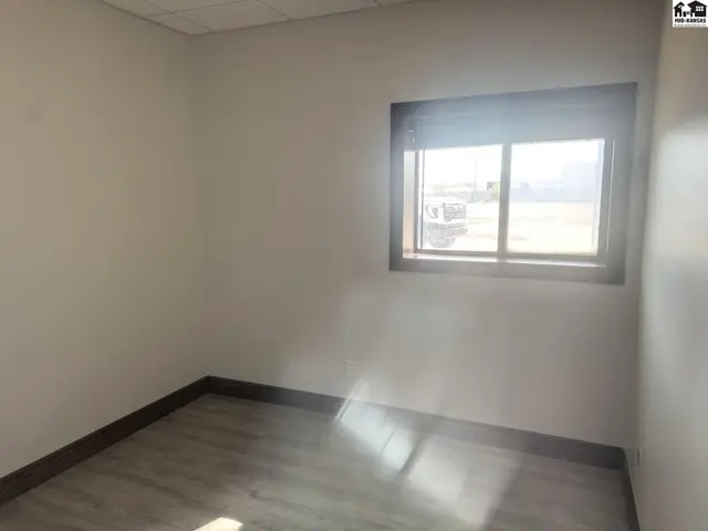 Empty room with light gray wood-look flooring, white walls, and a large window.