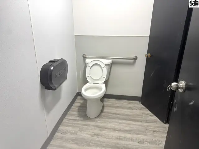 Accessible restroom with white toilet, gray walls, and wood-look flooring.