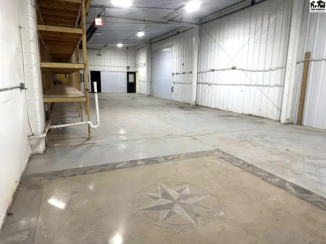 Spacious industrial space with concrete floors, metal walls, and built-in shelving.