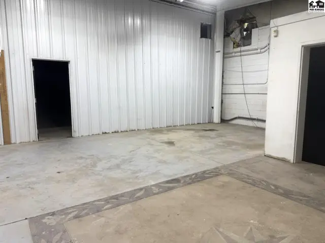 Spacious interior with corrugated metal walls, concrete floors, and a large open doorway.