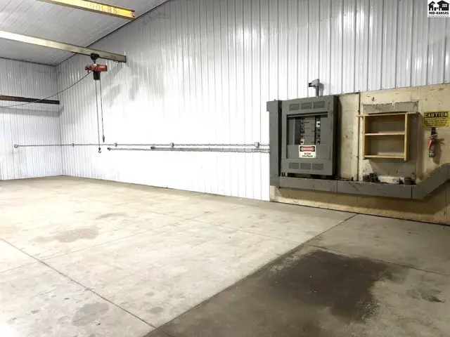 Spacious industrial space with concrete floors, white metal walls, and overhead crane.