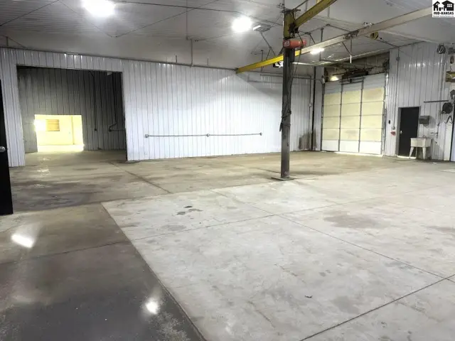 Spacious industrial interior with concrete floors, white metal walls, and large bay doors.