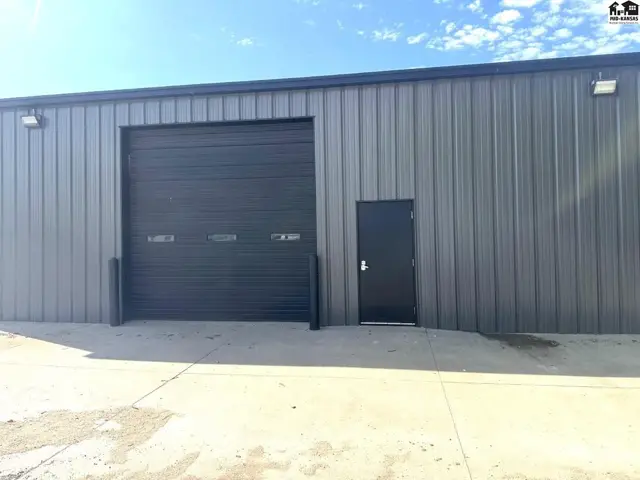 Gray metal industrial building exterior with a large roll-up door and a side entrance.