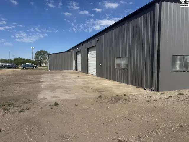 Exterior of a gray metal industrial building with multiple roll-up doors and concrete apron.