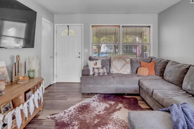 Spacious living room with a large sectional sofa, wood-look flooring, and a rustic media console.