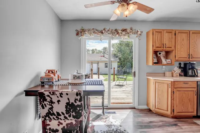 Dining area with cow-print chair and wood cabinets opens to a backyard deck.