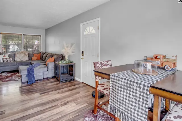 Living and dining area with gray sectional, wood floors, and a checkered tablecloth on the dining table.