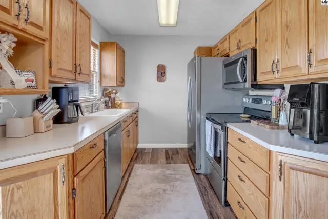 Spacious kitchen with light wood cabinets, stainless steel appliances, and white countertops.