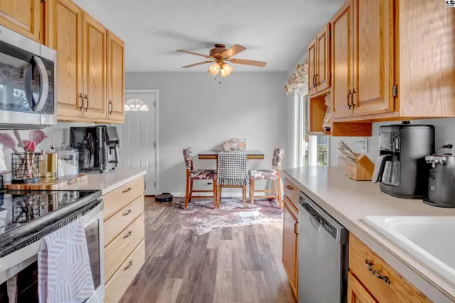 Kitchen with light wood cabinets, white countertops, stainless steel appliances, and dining area.