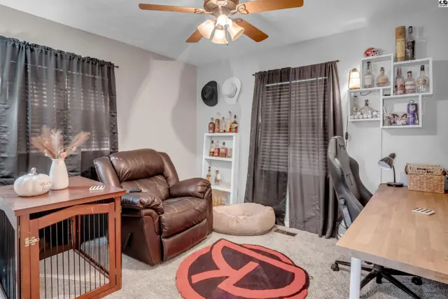 Cozy den with a leather recliner, wooden dog crate, and shelves displaying bottles.