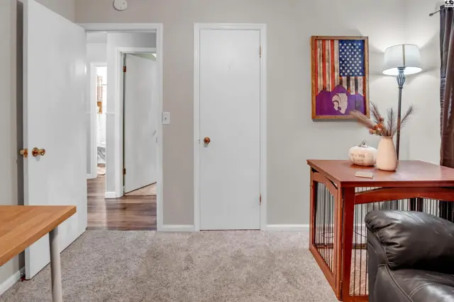 Cozy living area with plush carpet, a wooden table, and patriotic wall art.