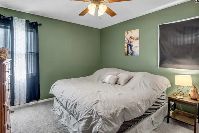 Cozy bedroom with a large bed, green walls, and a ceiling fan.