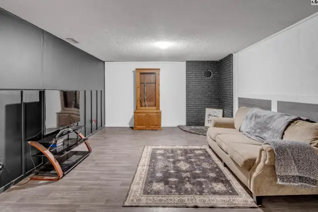 Spacious living room with dark wood floors, a beige sofa, and a vintage cabinet.