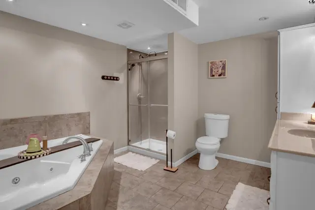 Spacious bathroom with a large soaking tub, glass-enclosed shower, and dual vanity with granite countertops.