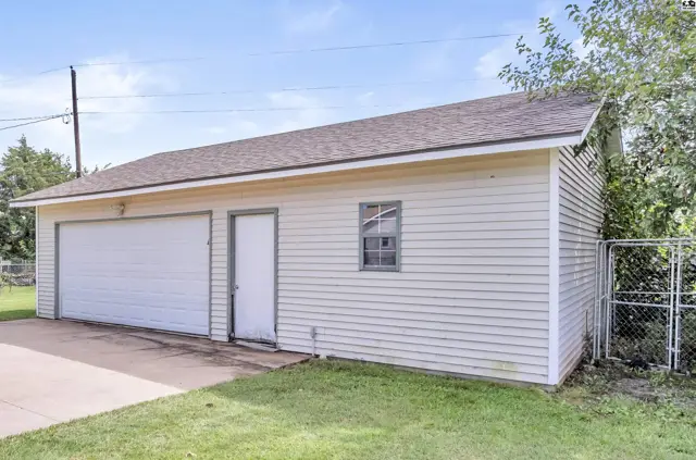 Two-car garage with white siding, a single door, and a small window, set on a grassy lawn.