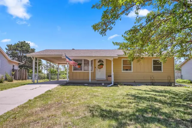 Yellow ranch home with a covered carport, white trim, and a welcoming front porch.