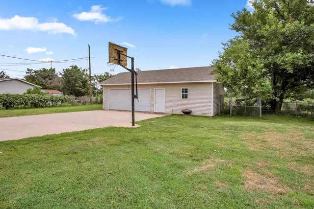 Two-car garage with a basketball hoop in the driveway, surrounded by a grassy yard.