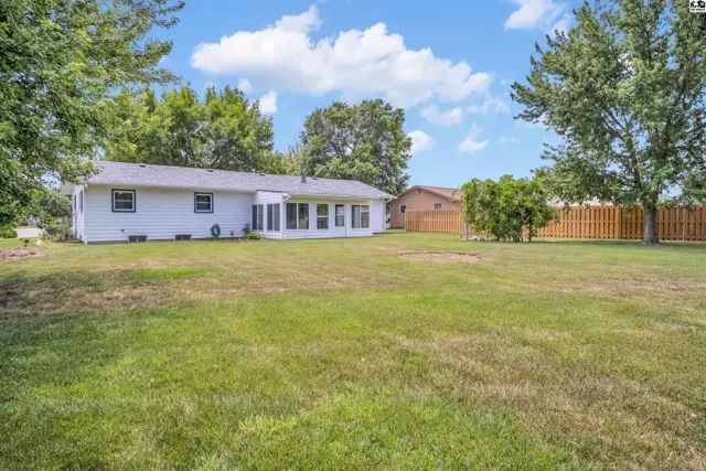 White ranch home with a sunroom addition and a large, grassy backyard.