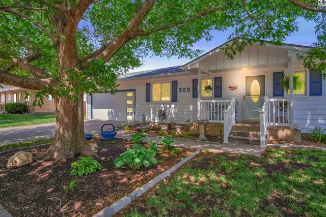 Charming white ranch home with blue shutters, a covered porch, and mature landscaping.