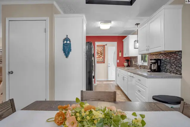 Bright white kitchen with granite countertops, mosaic backsplash, and red accent wall.