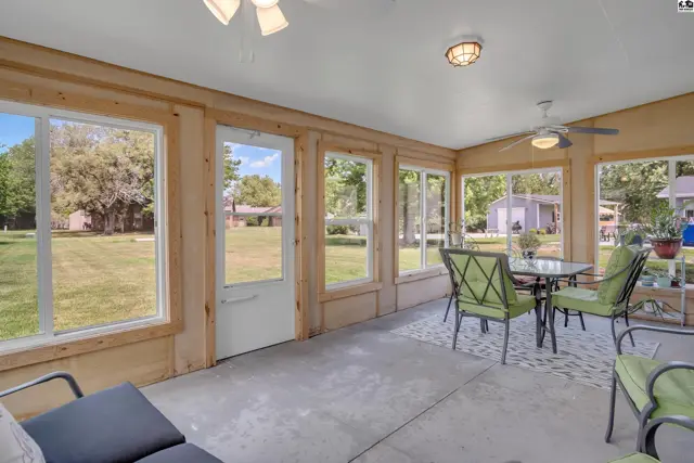 Sunroom with large windows, wood paneling, concrete floor, and a dining set.