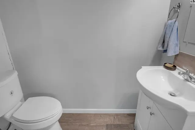 Modern bathroom with a white toilet, vanity, and sink against a light gray wall.