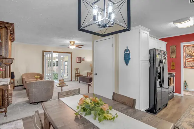 Dining area with dark wood table and floral centerpiece opens to a living room with plush seating.
