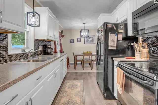 Bright kitchen with white cabinets, granite countertops, stainless steel appliances, and a dining area.