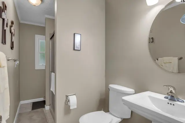 Modern bathroom with a white vanity, toilet, and a round mirror against neutral walls.