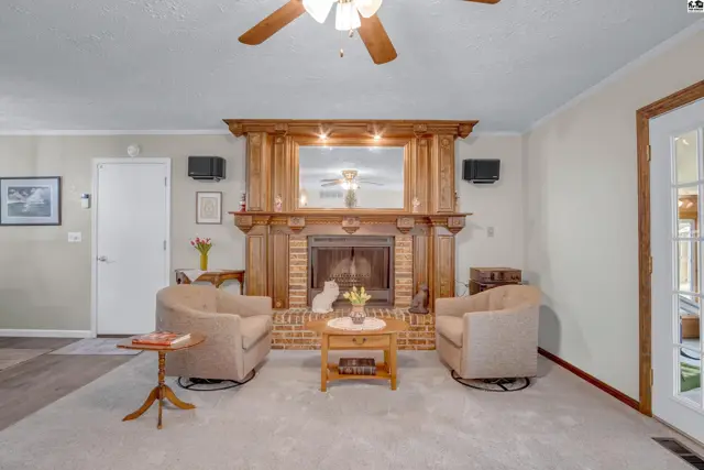 Living room with a brick fireplace, wood mantel, two armchairs, and a coffee table.