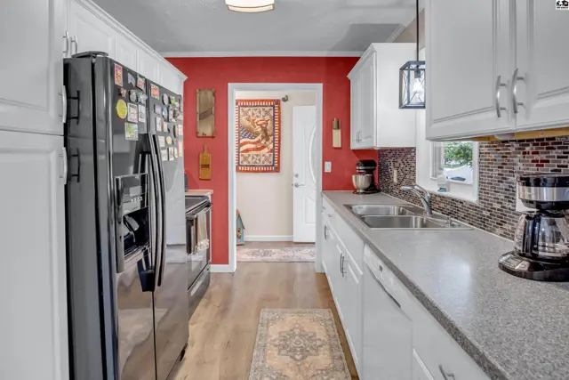 Modern kitchen with white cabinets, stainless steel appliances, and a bold red accent wall.