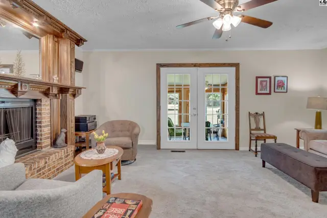 Spacious living room with brick fireplace, wood accents, and double doors leading outdoors.