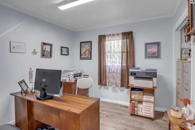 Light blue office with wood desk, printers, and framed art on pale walls.