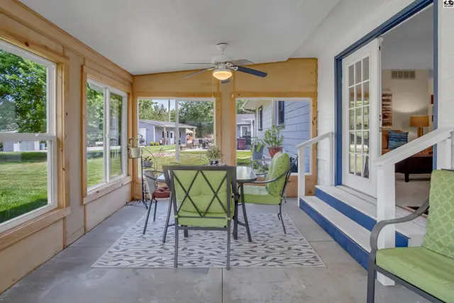 Sunroom with concrete floor, wood paneling, and glass doors opens to a patio with green outdoor furniture.