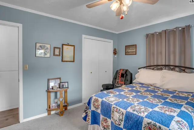 Light blue bedroom with a queen bed, white closet doors, and a small wooden side table.