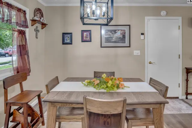 Dining room with a rustic wood table, chairs, and a modern chandelier.
