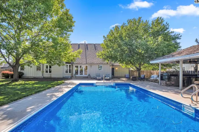 Spacious backyard with a large blue swimming pool, patio, and mature trees.