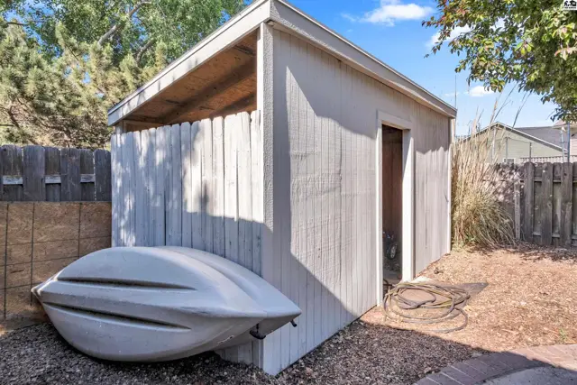 Exterior shed with a white wooden exterior, open door, and a boat stored beside it.