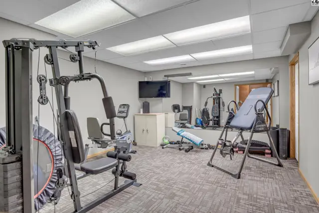 Home gym with weight machine, cardio equipment, inversion table, and mirrored wall.