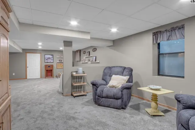 Spacious finished basement with plush gray carpet, neutral walls, and comfortable seating.